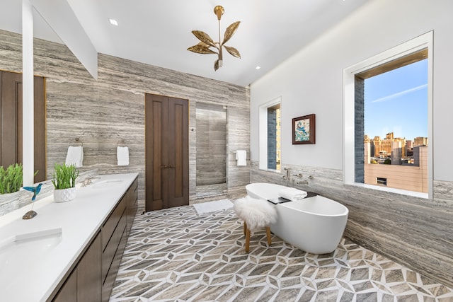 bathroom with a bath, vanity, and tile walls