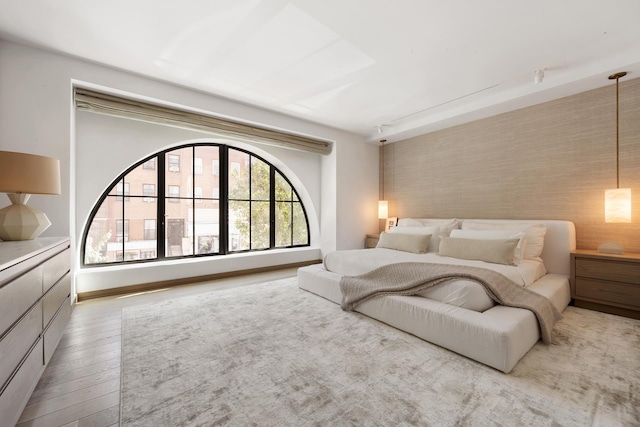 bedroom with an accent wall, wood finished floors, and baseboards