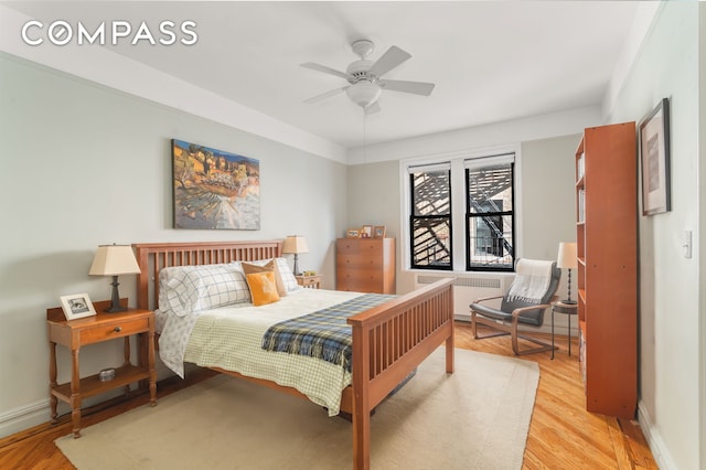 bedroom with light wood-style flooring, radiator, baseboards, and ceiling fan