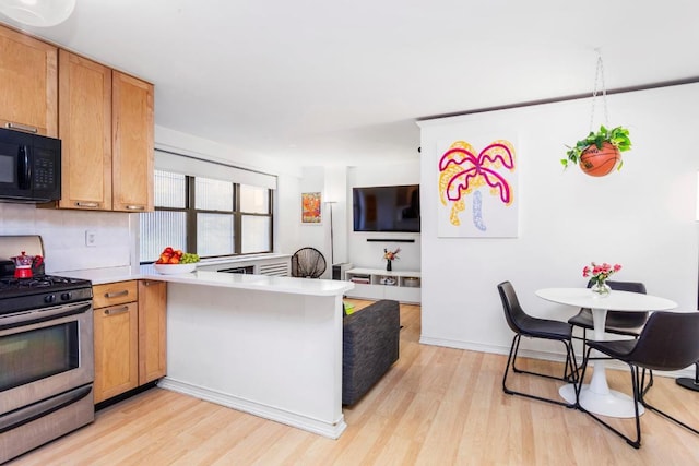 kitchen featuring light hardwood / wood-style flooring, decorative backsplash, stainless steel gas range oven, and kitchen peninsula