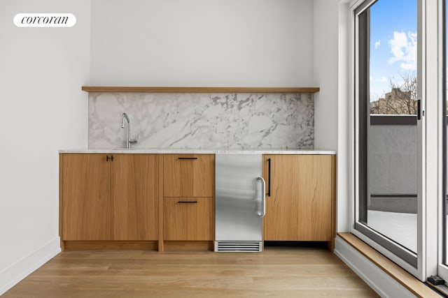 bar with visible vents, light wood finished floors, stainless steel refrigerator, decorative backsplash, and a sink