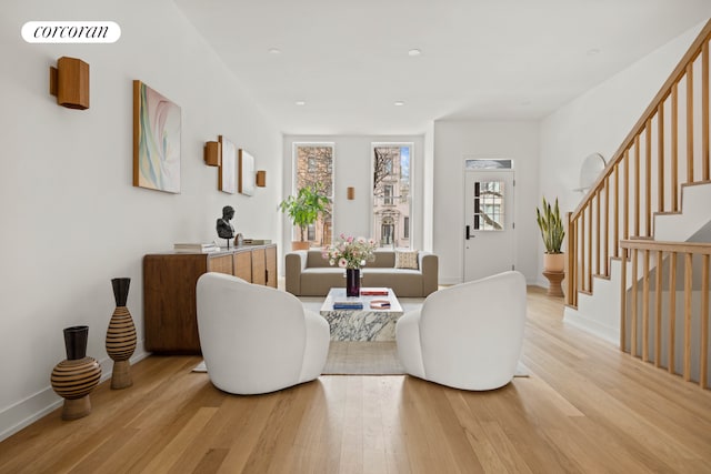 living area with a wealth of natural light, light wood-type flooring, visible vents, and stairs