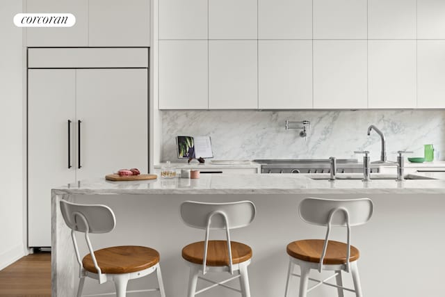 kitchen with paneled built in fridge, light stone countertops, and modern cabinets