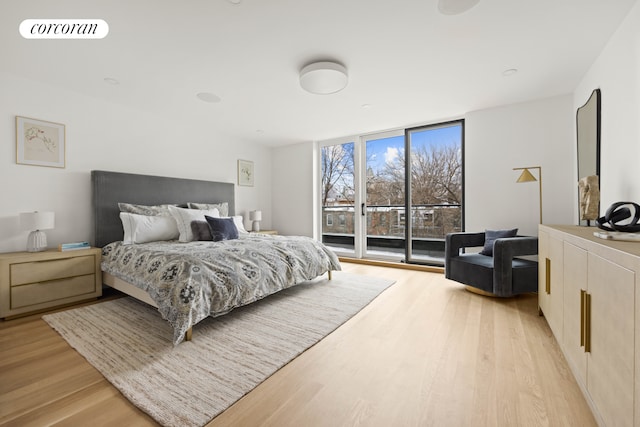 bedroom featuring a wall of windows, light wood-style flooring, visible vents, and access to exterior