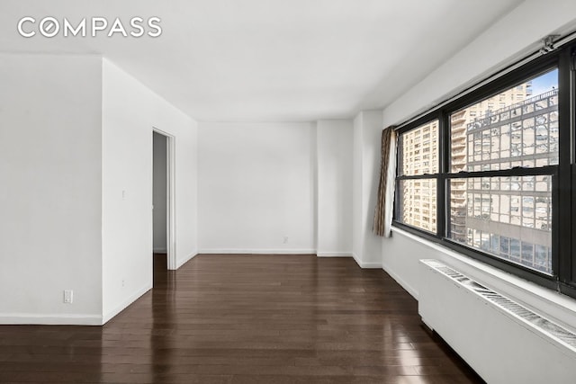 unfurnished room featuring radiator heating unit and dark wood-type flooring