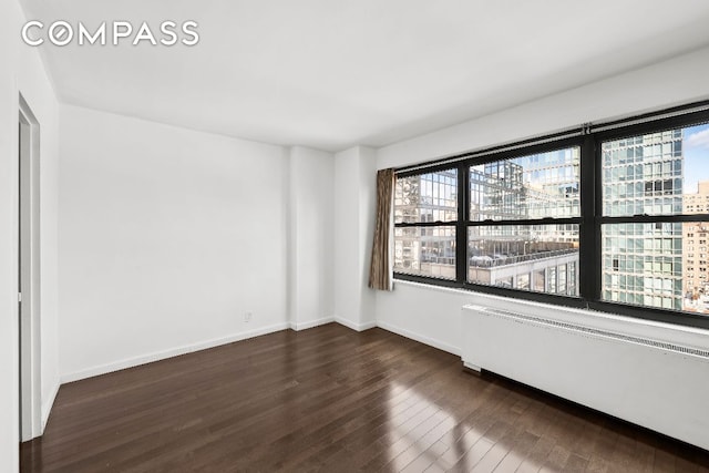 unfurnished room with dark hardwood / wood-style floors and radiator