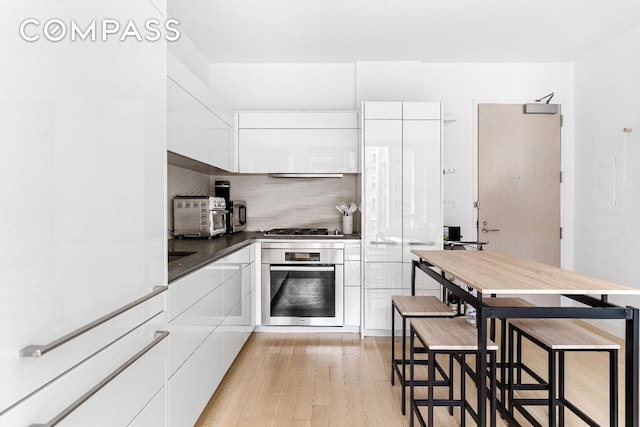 kitchen featuring white cabinetry, tasteful backsplash, stainless steel appliances, and light hardwood / wood-style flooring