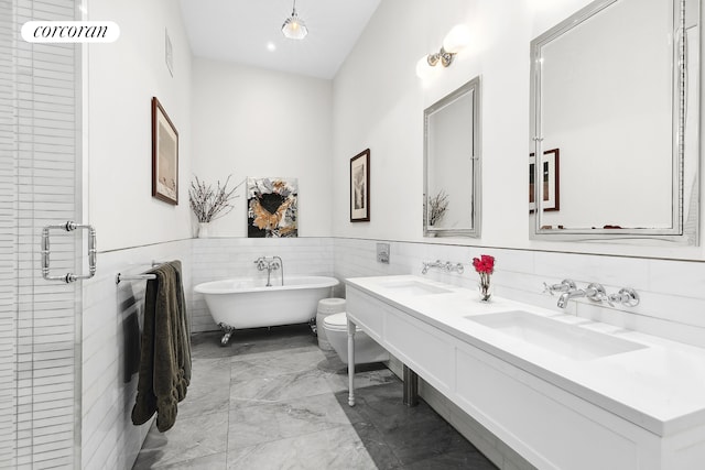 79 Worth St Unit 4R, New York City, NY 10013 - full bathroom featuring marble look tiles, double vanity, toilet, tile walls, and a freestanding tub