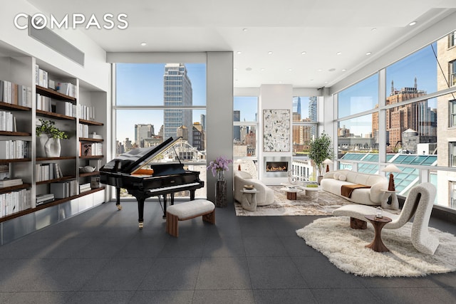 interior space featuring a glass covered fireplace, plenty of natural light, a city view, and expansive windows