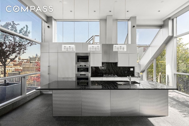 kitchen featuring sink, dark stone countertops, white cabinets, and a towering ceiling