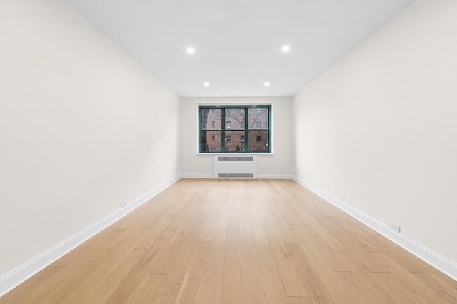 spare room featuring radiator, light wood finished floors, baseboards, and recessed lighting