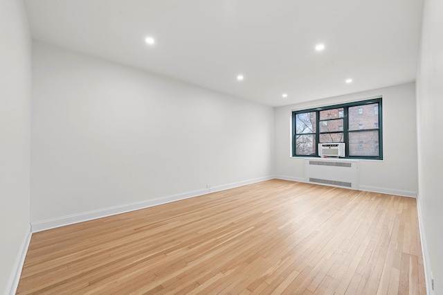 spare room featuring radiator, cooling unit, baseboards, recessed lighting, and light wood-type flooring