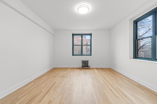 empty room featuring radiator heating unit and light wood-type flooring