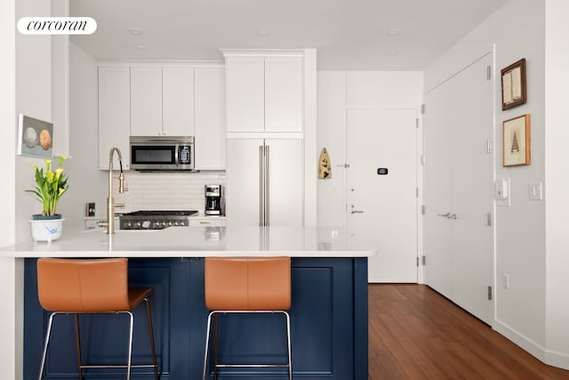 kitchen with stainless steel microwave, white cabinetry, gas range oven, light countertops, and freestanding refrigerator