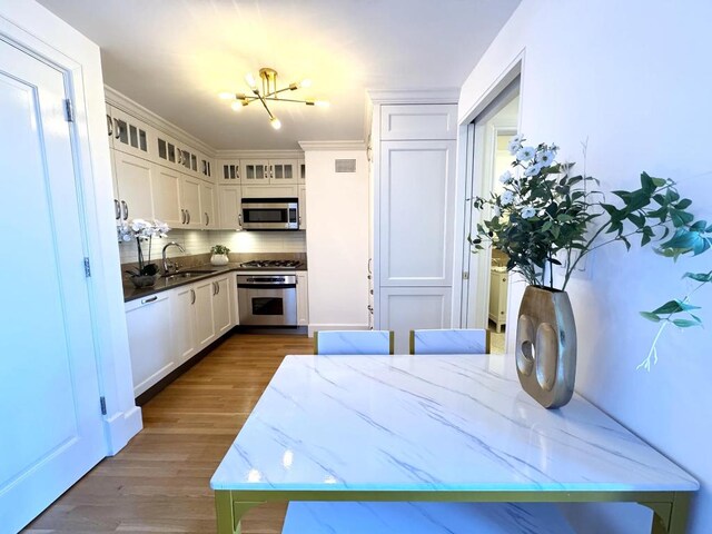 kitchen featuring appliances with stainless steel finishes, dark hardwood / wood-style floors, white cabinetry, sink, and decorative backsplash