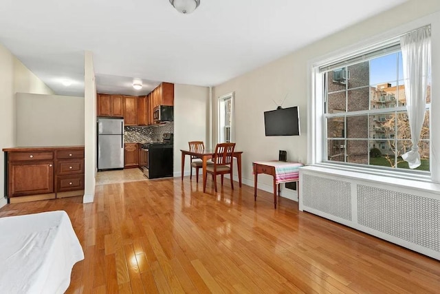 living room featuring a healthy amount of sunlight, radiator, and light hardwood / wood-style floors