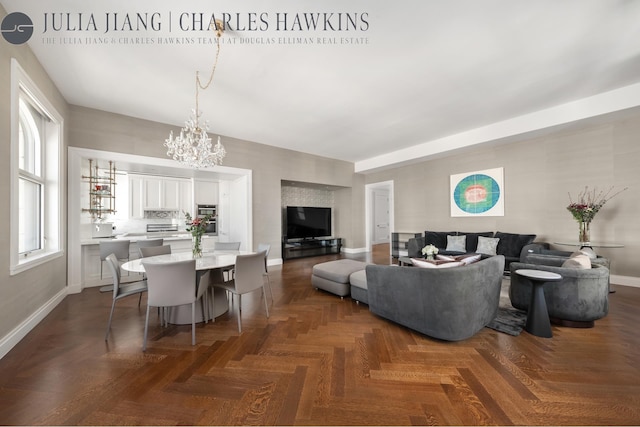 living area featuring baseboards and a chandelier