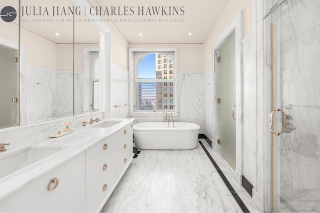 full bathroom featuring wainscoting, a sink, double vanity, marble finish floor, and a soaking tub