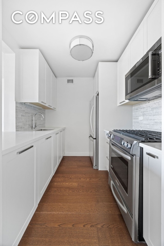200 E 94th St Unit 2012, New York City, NY 10128 - kitchen featuring stainless steel appliances, decorative backsplash, light countertops, white cabinetry, and dark wood-style flooring
