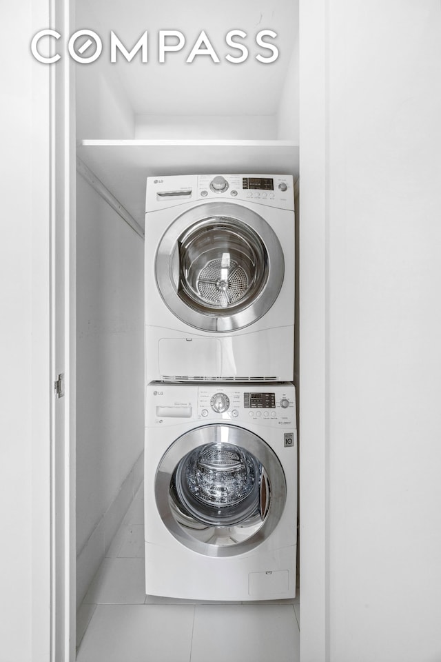 laundry room featuring stacked washer / drying machine and tile patterned flooring