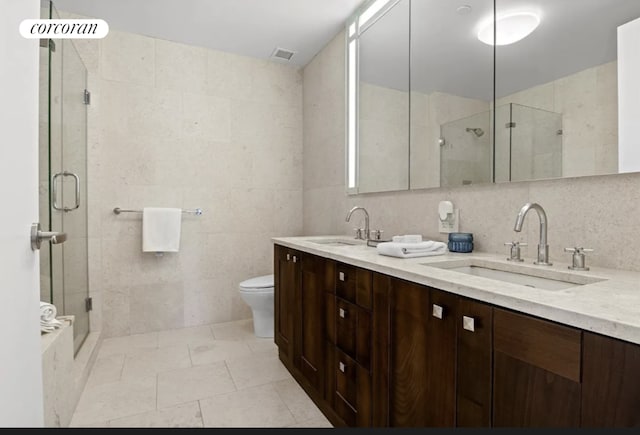 bathroom with vanity, toilet, tile walls, and a shower with shower door