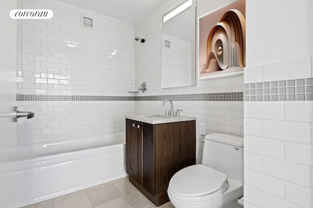 full bathroom with tiled shower / bath, tile walls, vanity, toilet, and tile patterned floors