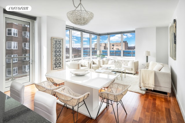 living room with breakfast area, hardwood / wood-style flooring, and a wall of windows