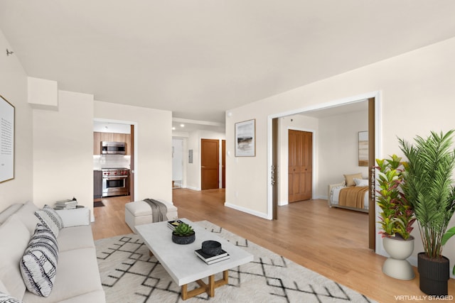 living room with light wood finished floors, recessed lighting, and baseboards