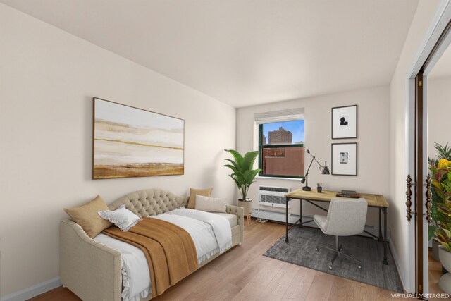 bedroom with a wall mounted air conditioner and light wood-type flooring