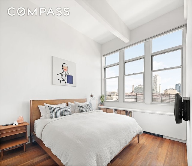 bedroom with beamed ceiling and hardwood / wood-style flooring