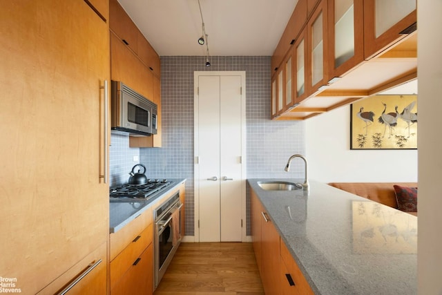 kitchen with appliances with stainless steel finishes, sink, decorative backsplash, and dark stone counters