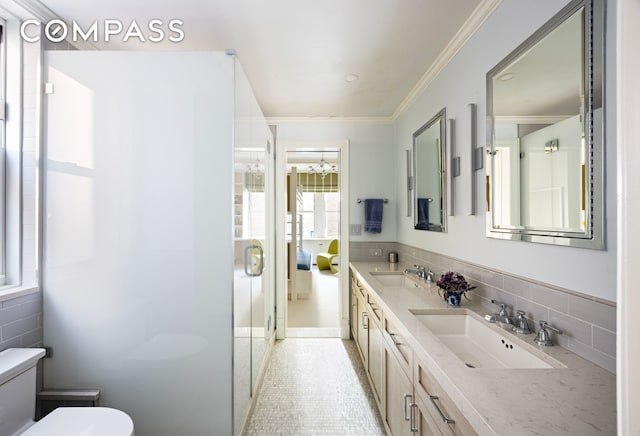 bathroom featuring toilet, a stall shower, ornamental molding, a sink, and decorative backsplash