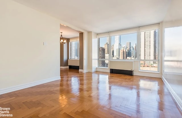 unfurnished room featuring parquet floors and a chandelier