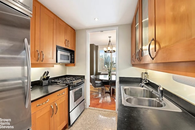 kitchen with brown cabinets, a sink, dark countertops, appliances with stainless steel finishes, and glass insert cabinets