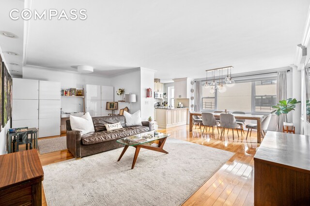 living room with crown molding and light hardwood / wood-style floors