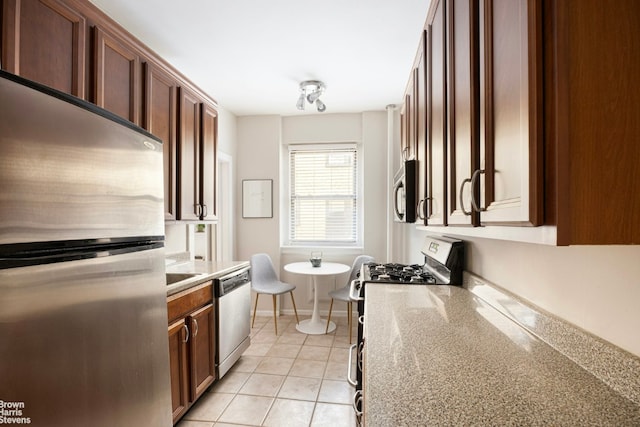 kitchen featuring light tile patterned floors, light stone countertops, and appliances with stainless steel finishes