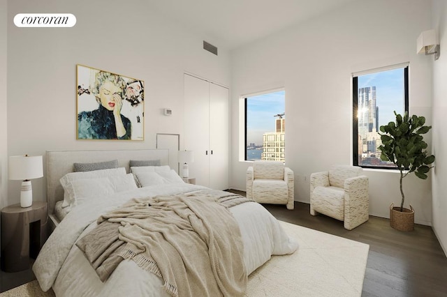 bedroom featuring multiple windows, visible vents, a city view, and wood finished floors