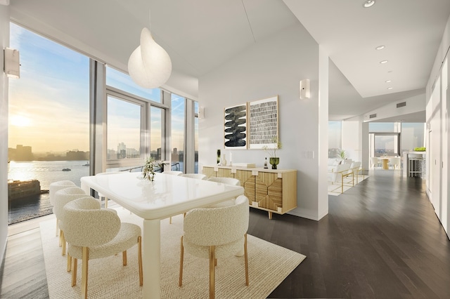 dining area featuring expansive windows, a water view, and dark hardwood / wood-style floors