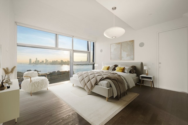 bedroom featuring hardwood / wood-style flooring, a water view, access to exterior, and high vaulted ceiling