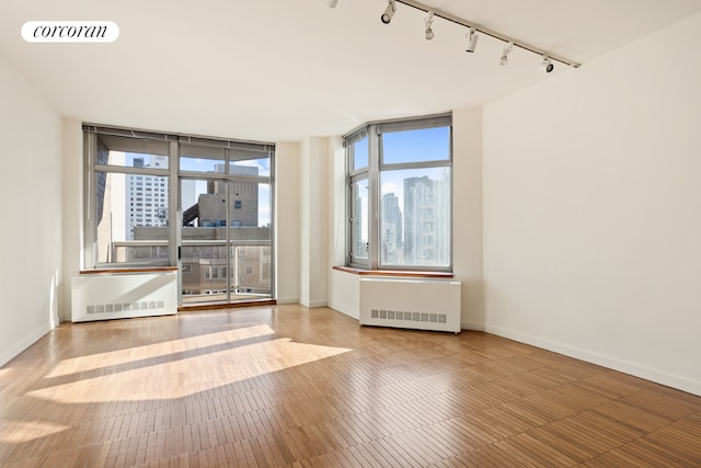 unfurnished room with hardwood / wood-style flooring, a healthy amount of sunlight, and radiator heating unit