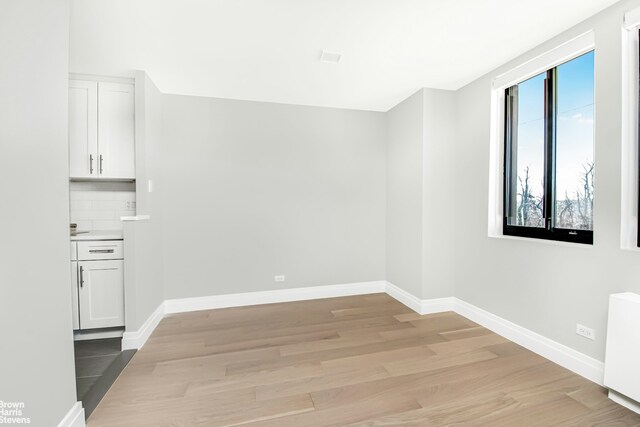 unfurnished dining area featuring radiator heating unit, light wood-style flooring, and baseboards