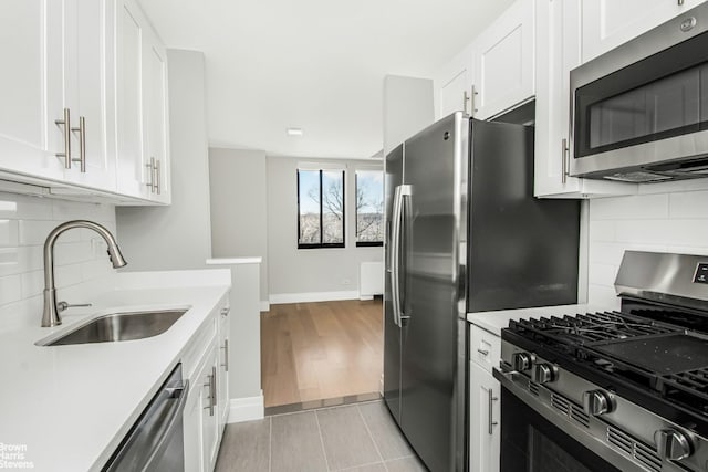 kitchen featuring a sink, white cabinetry, stainless steel appliances, and light countertops