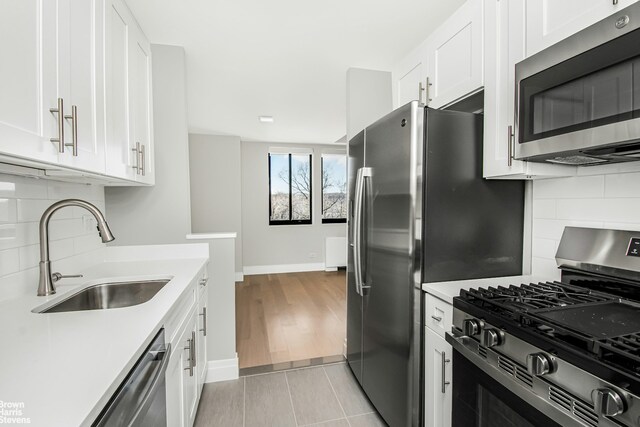 kitchen featuring a sink, tasteful backsplash, appliances with stainless steel finishes, white cabinets, and light countertops