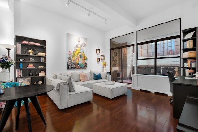 living room featuring beamed ceiling, dark wood-type flooring, and track lighting