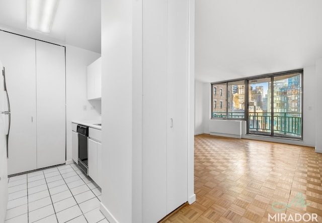 kitchen with black dishwasher, light parquet flooring, and white cabinets