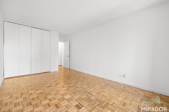 unfurnished bedroom featuring light parquet flooring and a closet