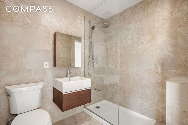 bathroom featuring vanity, tile walls, toilet, and tiled shower