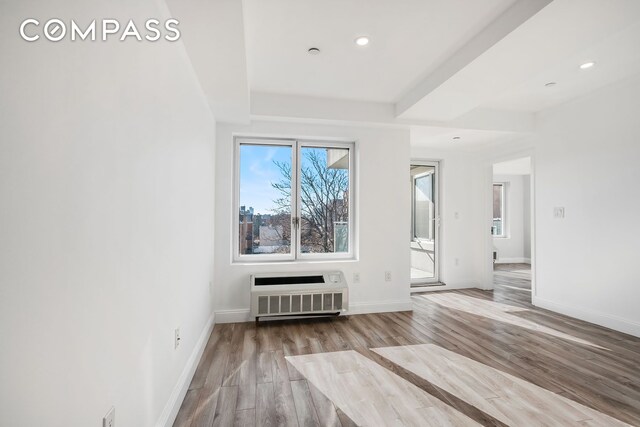 unfurnished room with a wall mounted AC and light wood-type flooring