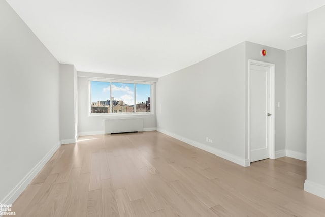 spare room featuring radiator heating unit and light hardwood / wood-style flooring