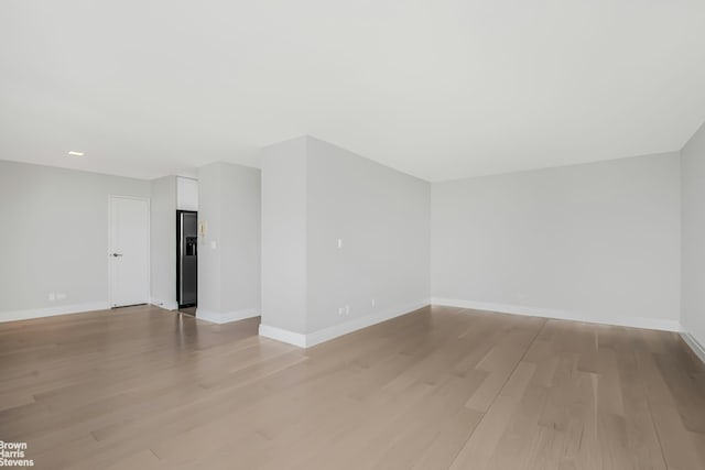 spare room with baseboards and light wood finished floors